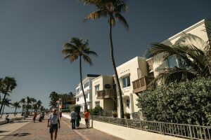 People walking on a sidewalk with palm trees